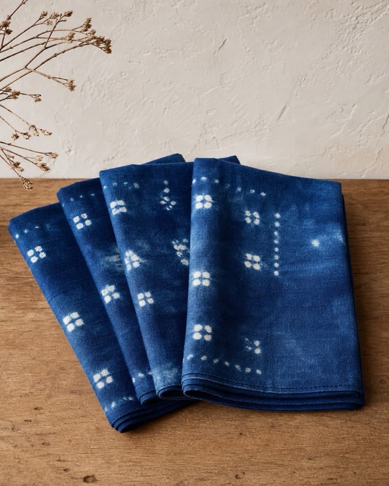 Set of four natural indigo napkins folded on a wood table